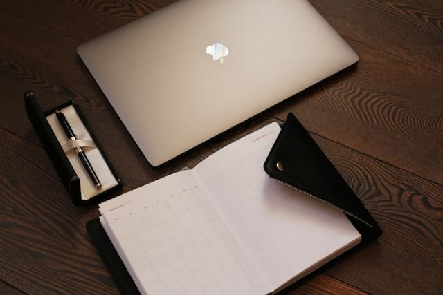 laptop and planner on a dark wood desk